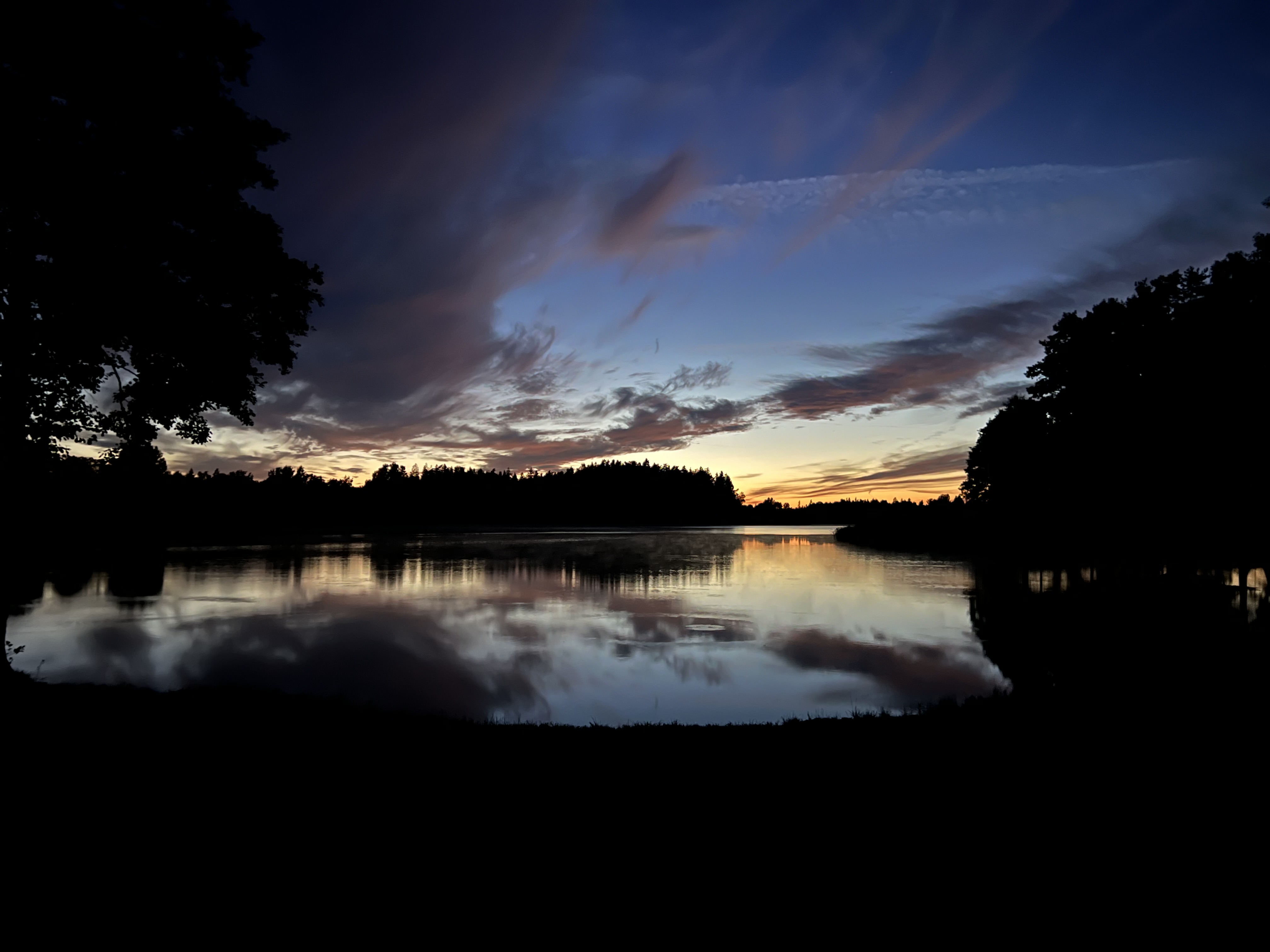 A dramatic summer sunset reflected across the lake at Ezermaļi
