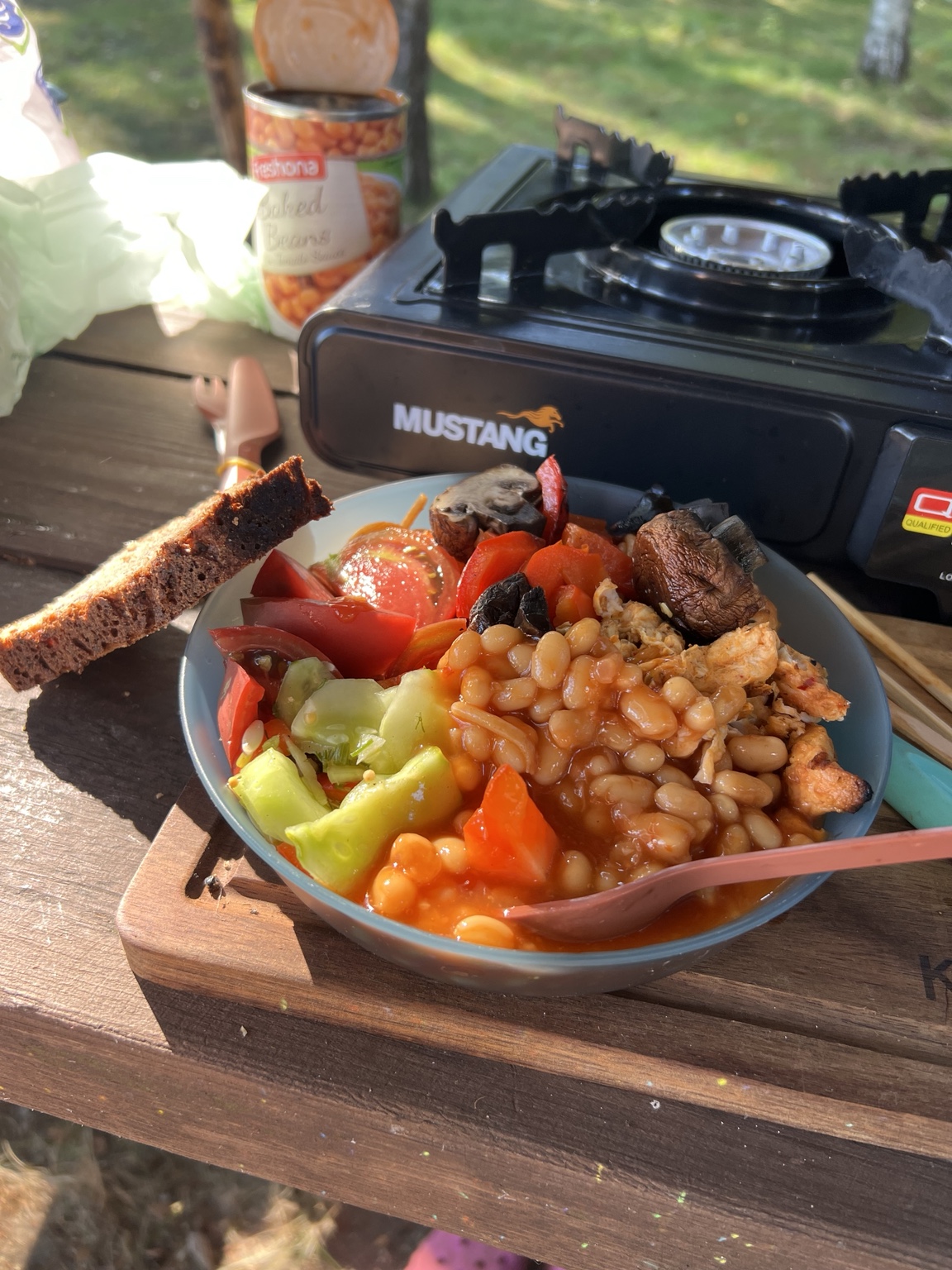 Breakfast of baked beans, barbecue leftovers, fresh vegetables and homemade rye bread at the campsite