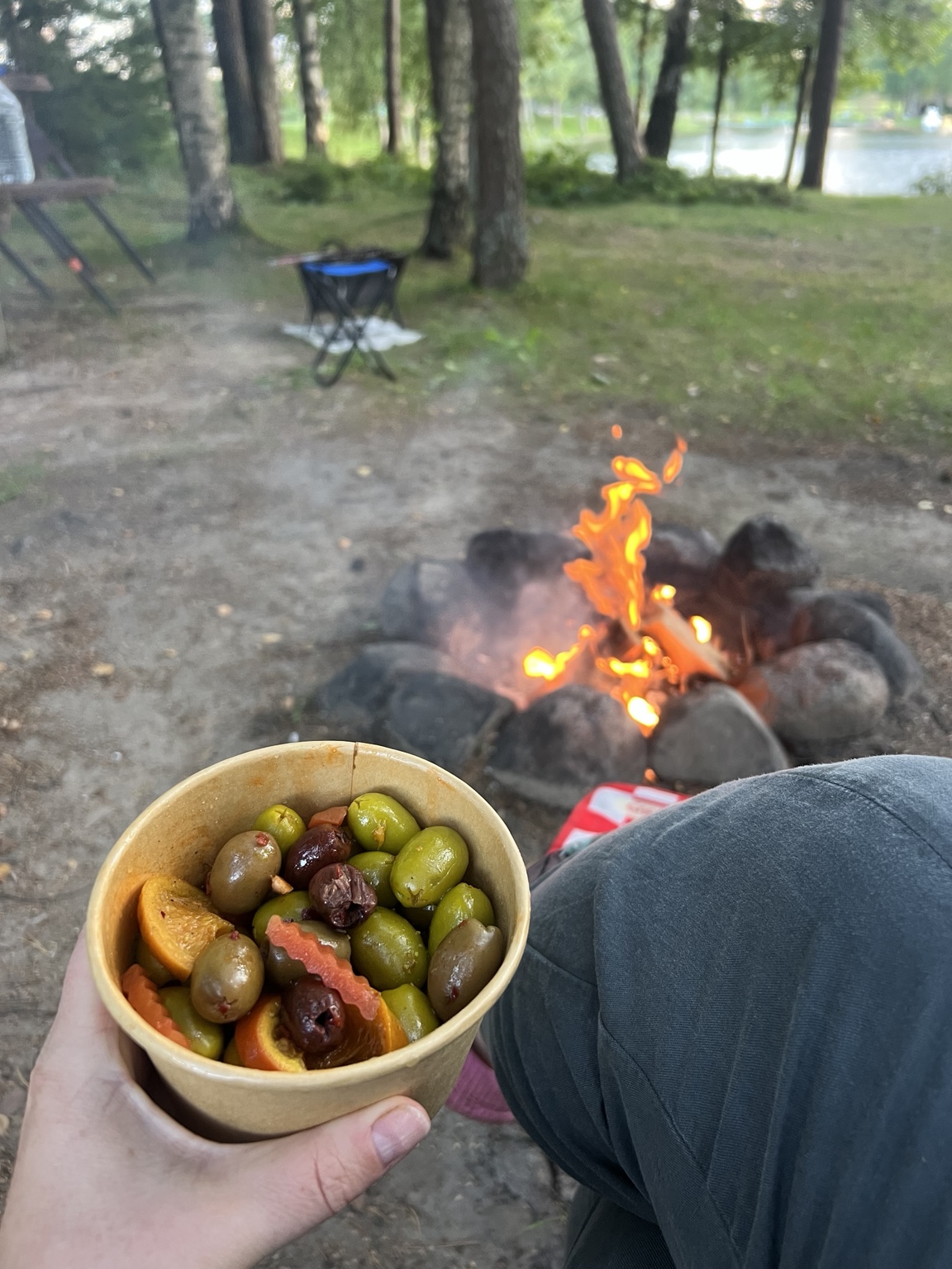 A cup of marinated olives held beside the campfire