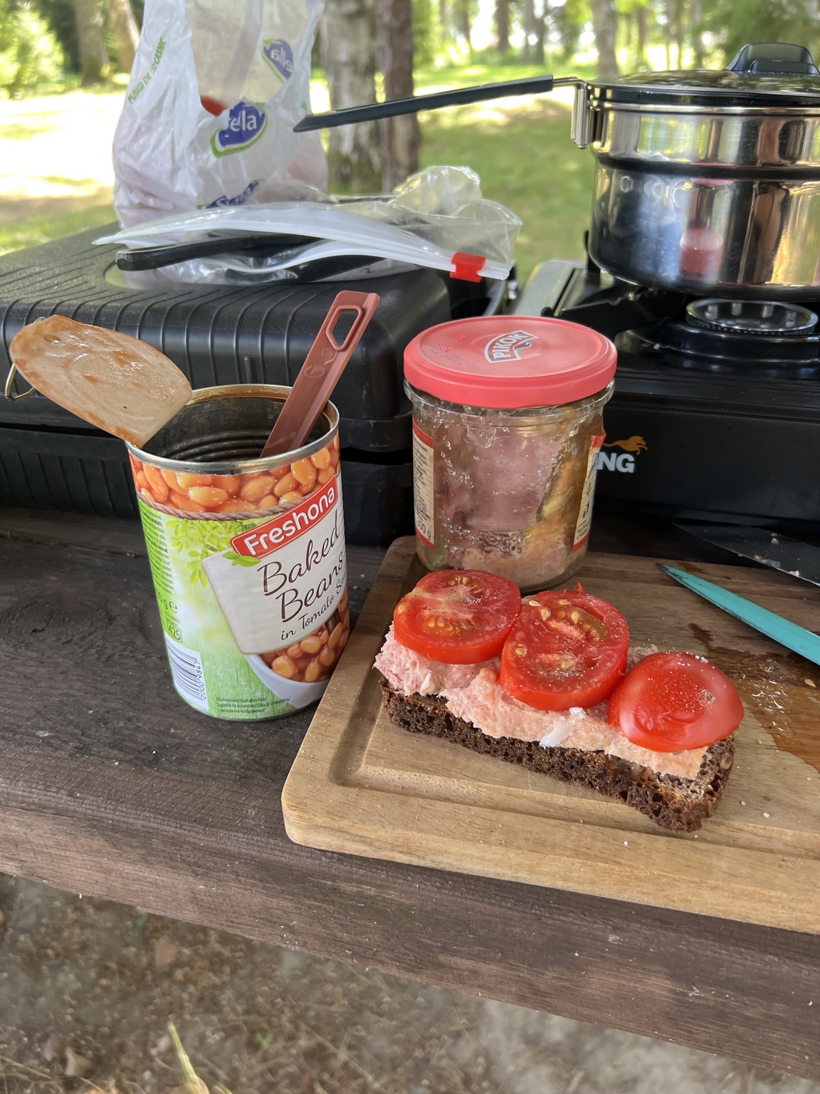 Homemade rye bread topped with tinned sautéed pork and tomato beside baked beans