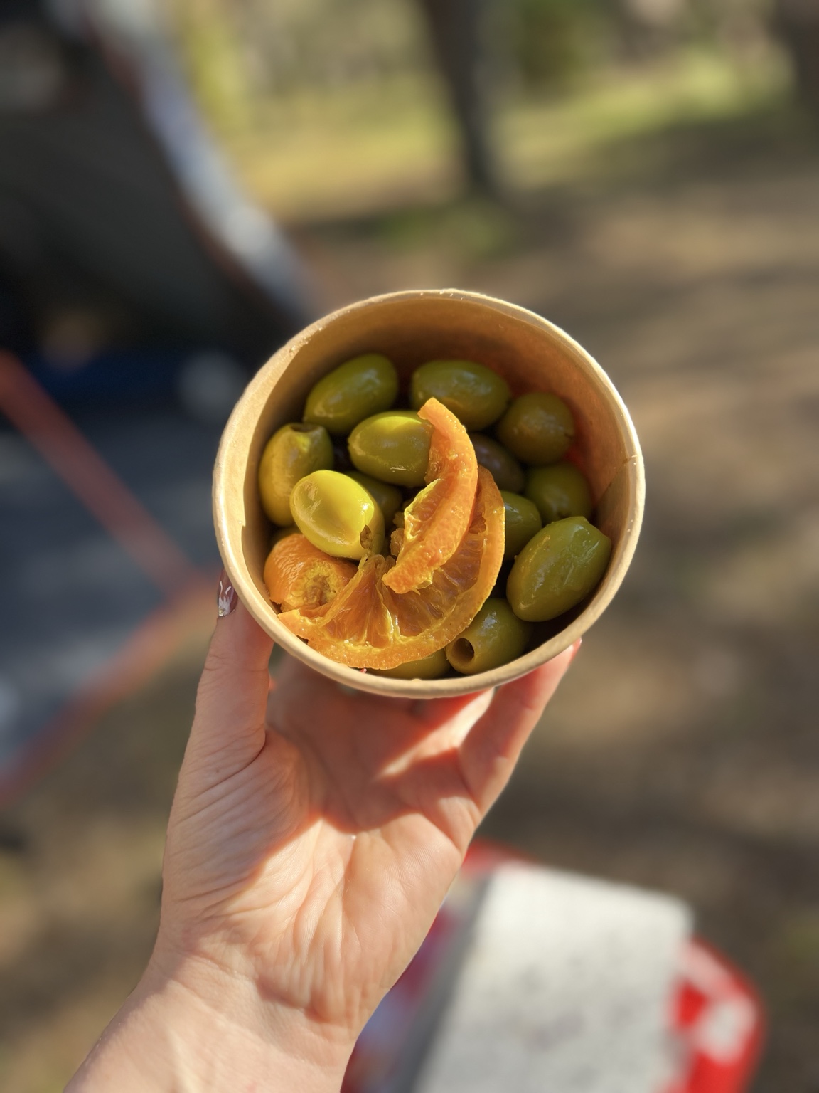 A cup of marinated green olives with orange slices at the campsite